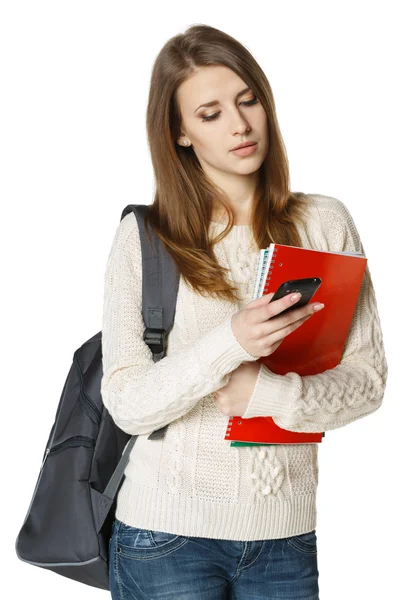 Estudiante con mochila y libros enviando un sms en el teléfono celular —  Fotos de Stock