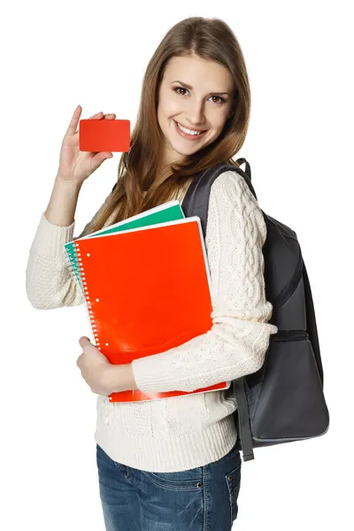 Mulher vestindo uma mochila e segurando cadernos mostrando cartão de crédito em branco — Fotografia de Stock