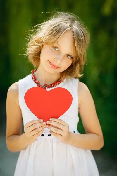Flickan kikar ut från kanten av hjärta form — Stockfoto
