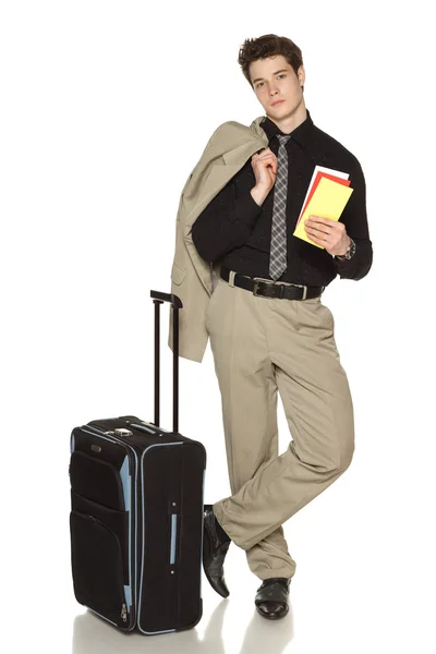 Jovem empresário em pé com estojo de viagem e segurando bilhetes — Fotografia de Stock