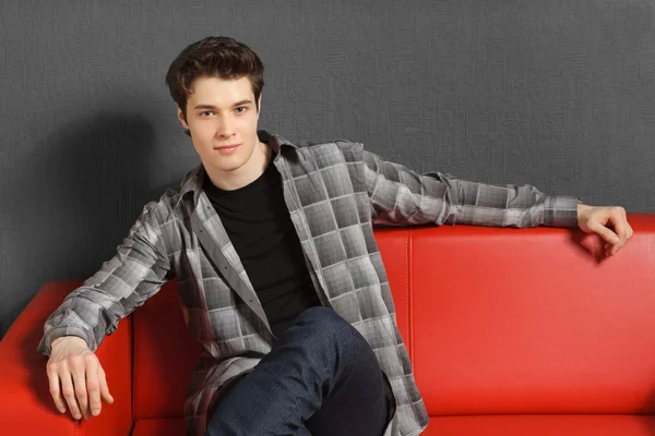 Man relaxing sitting on the red sofa — Stock Photo, Image