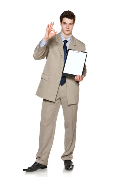 Longitud completa de joven empresario sosteniendo pizarra blanca en blanco mostrando gesto OK — Foto de Stock