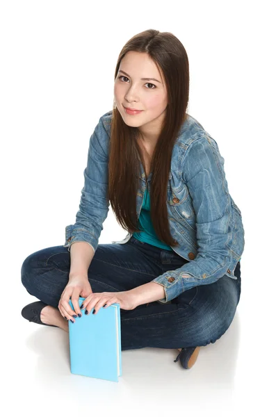 Χαμογελώντας χαλαρή φοιτήτριας που κάθεται στο πάτωμα με ένα βιβλίο — Φωτογραφία Αρχείου