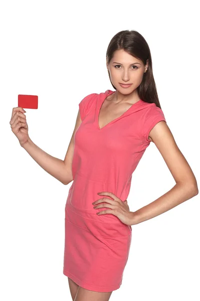 Joven mujer usando estilo deportivo vestido rosa mostrando tarjeta de crédito en blanco —  Fotos de Stock