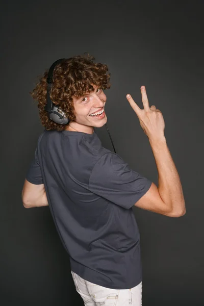 Happy male in headphones gesturing V sign — Stock Photo, Image