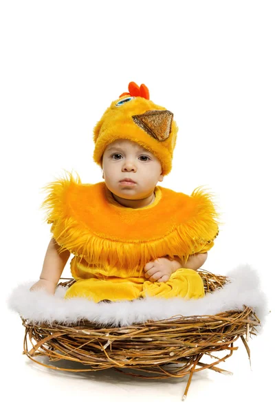 Baby sitting in nest in chicken costume — Stock Photo, Image