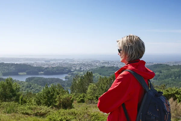 Vrouw met rugzak genieten van uitzicht op de stad vallei — Stockfoto
