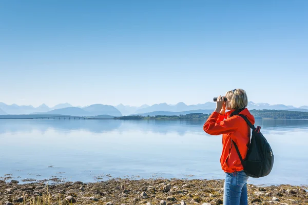 Woman tourist looking through binoculars — Stock Photo, Image