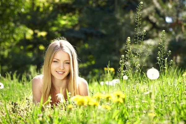 Frühlingsmädchen auf dem Löwenzahnfeld liegend — Stockfoto