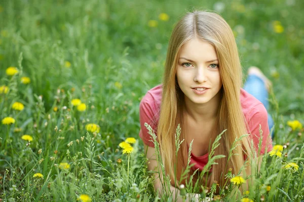 春のタンポポのフィールドの上に横たわる女の子 — ストック写真