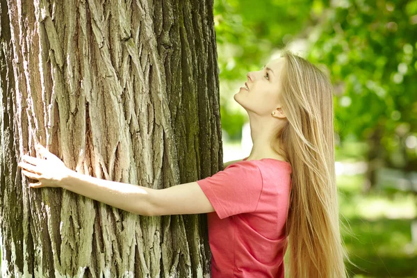 Mulher abraçando uma árvore, olhando para cima — Fotografia de Stock