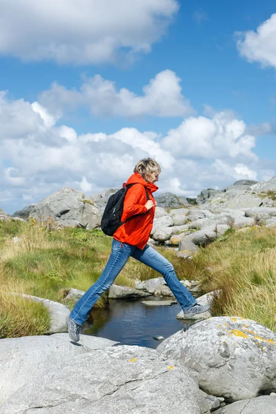 Vrouw wandelaar springt over stenen — Stockfoto