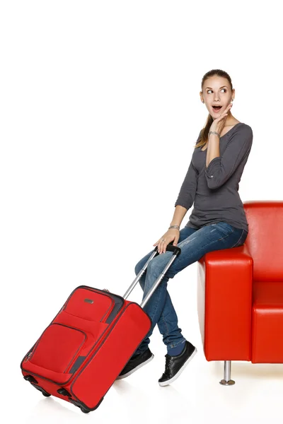 Happy female on sofa with suitcase — Stock Photo, Image