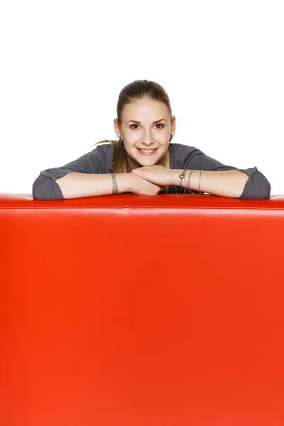 Mulher apoiada no sofá de couro vermelho — Fotografia de Stock
