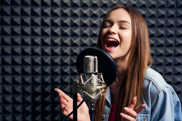 Gadis remaja di studio rekaman dengan mic di atas latar belakang panel penyerap akustik — Stok Foto