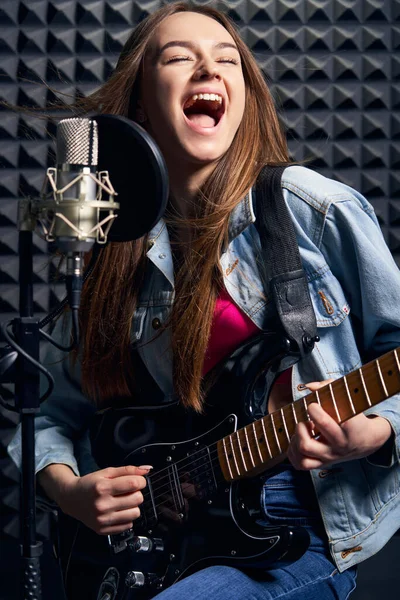 Girl musisi di studio rekaman bermain gitar listrik dan bernyanyi di mic — Stok Foto