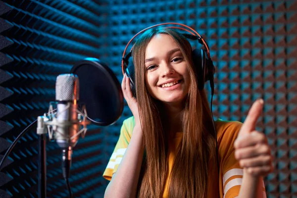 Teen girl im Tonstudio mit Mikrofon über akustischem Panel Hintergrund — Stockfoto