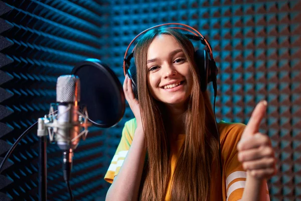 Chica adolescente en estudio de grabación con micrófono sobre fondo de panel acústico —  Fotos de Stock