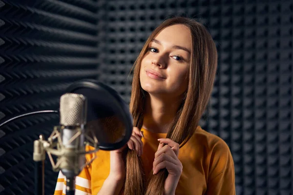Chica adolescente en estudio de grabación con micrófono sobre fondo de panel acústico —  Fotos de Stock