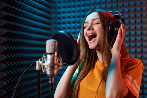 Gadis remaja di studio rekaman dengan mic di atas latar belakang panel penyerap akustik — Stok Foto