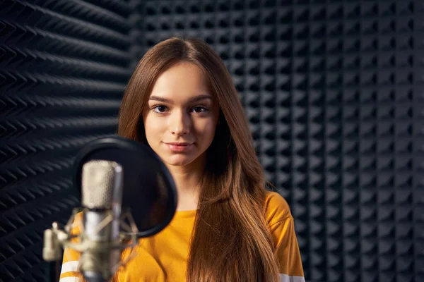 Adolescente em estúdio de gravação com microfone sobre fundo painel acústico — Fotografia de Stock