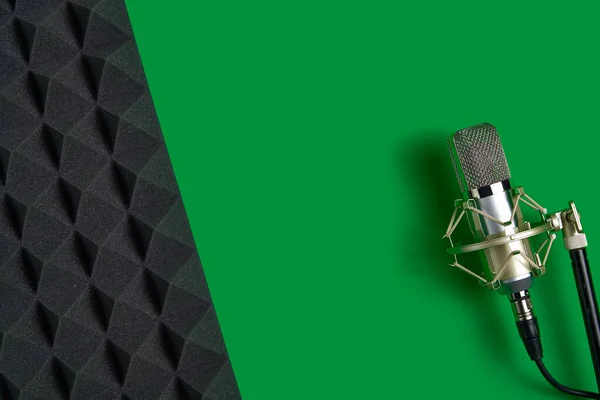 Mikrofon zöld háttérrel, fénymásoló felülettel és akusztikus habbal — Stock Fotó
