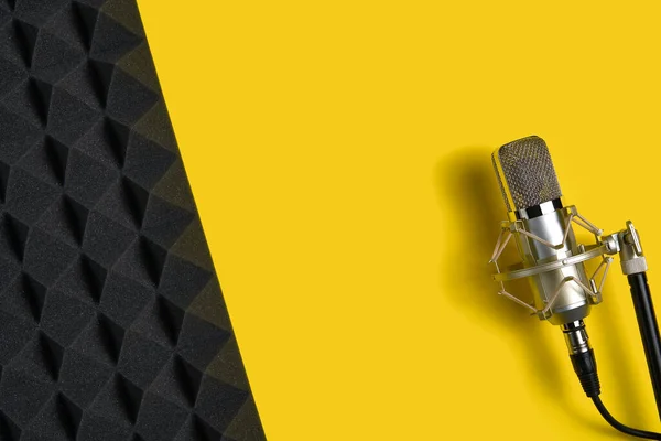 黄色の背景とテキスト フラットレイアウトのための負のスペースと音響フォームパネル上のマイク — ストック写真