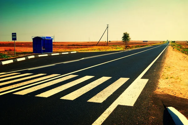 Fermata autobus e autostrada lungo il campo — Foto Stock