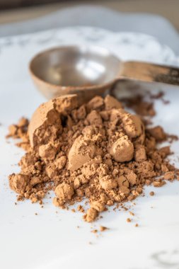 Kakao tozlu metal kaşık beyaz arka planda.