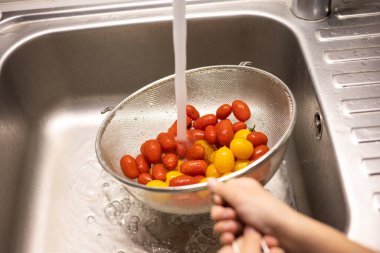 Çocukların elleri mutfakta vişneli domates yıkıyor.