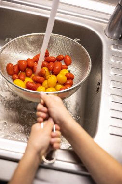 Çocukların elleri mutfakta vişneli domates yıkıyor.