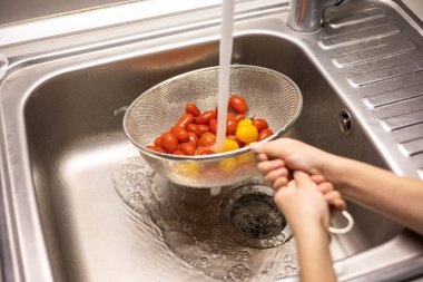 Çocukların elleri mutfakta vişneli domates yıkıyor.