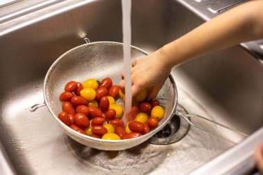 Çocukların elleri mutfakta vişneli domates yıkıyor.