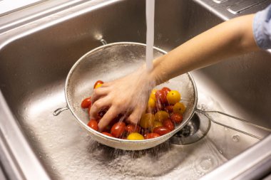 Çocukların elleri mutfakta vişneli domates yıkıyor.