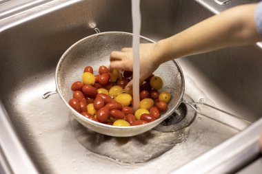 Çocukların elleri mutfakta vişneli domates yıkıyor.