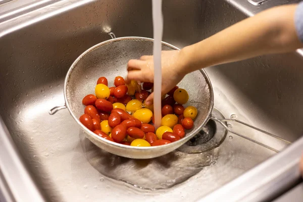 Çocukların elleri mutfakta vişneli domates yıkıyor.