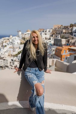 Genç, güzel bir kadın merdivenlerden yukarı çıkıyor denizin arka planına ve Oia Santorini Yunanistan 'ın mimarisine karşı.