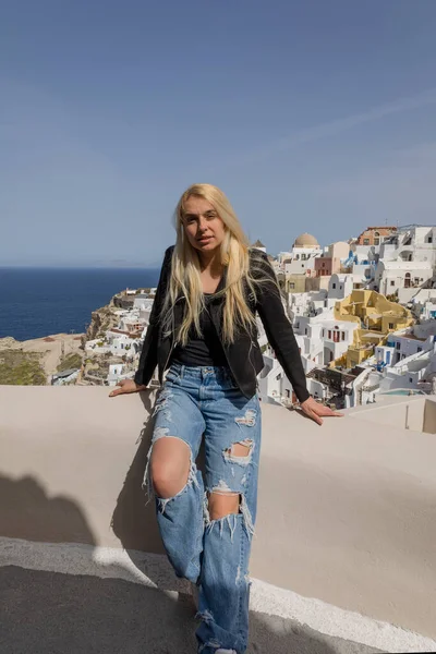 Genç, güzel bir kadın merdivenlerden yukarı çıkıyor denizin arka planına ve Oia Santorini Yunanistan 'ın mimarisine karşı.