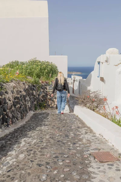 Genç, güzel bir kadın merdivenlerden yukarı çıkıyor denizin arka planına ve Oia Santorini Yunanistan 'ın mimarisine karşı.