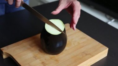 Evde, tahta masada patlıcan kesmek.