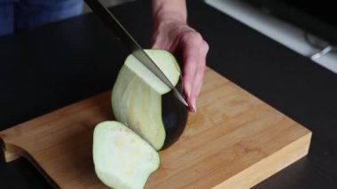 Evde, tahta masada patlıcan kesmek.