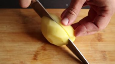 man hands cutting peeled potatoes close up on wooden board