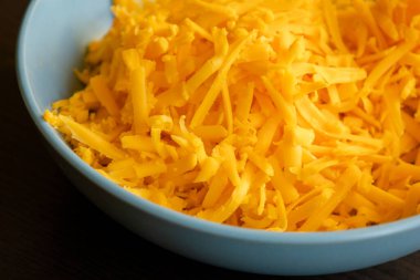 grated cheddar cheese on a plate on wood table