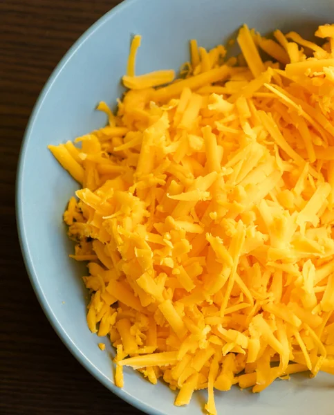 stock image grated cheddar cheese on a plate on wood table