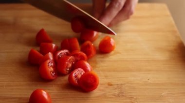 cutting cherry tomatoes at home on wooden board