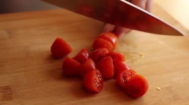 cutting cherry tomatoes at home on wooden board