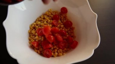 cooking preparing  mediterranean salad with beans corn and cherry tomatoes