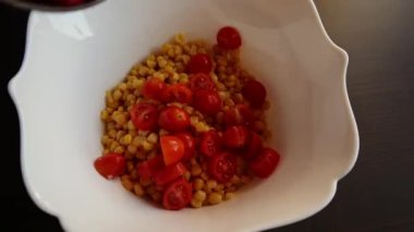 cooking preparing  mediterranean salad with beans corn and cherry tomatoes