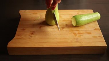 cutting zucchini on wooden chopping board