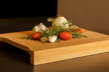 close-ups of tomatoes, rosemary and garlic on wooden board